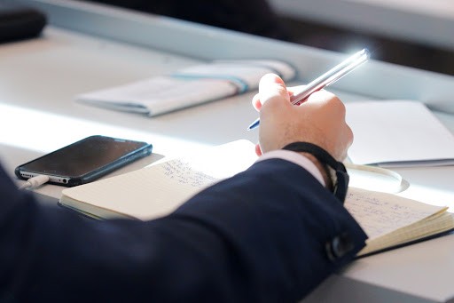 A person in a suit writing down ideas for a speech or work.